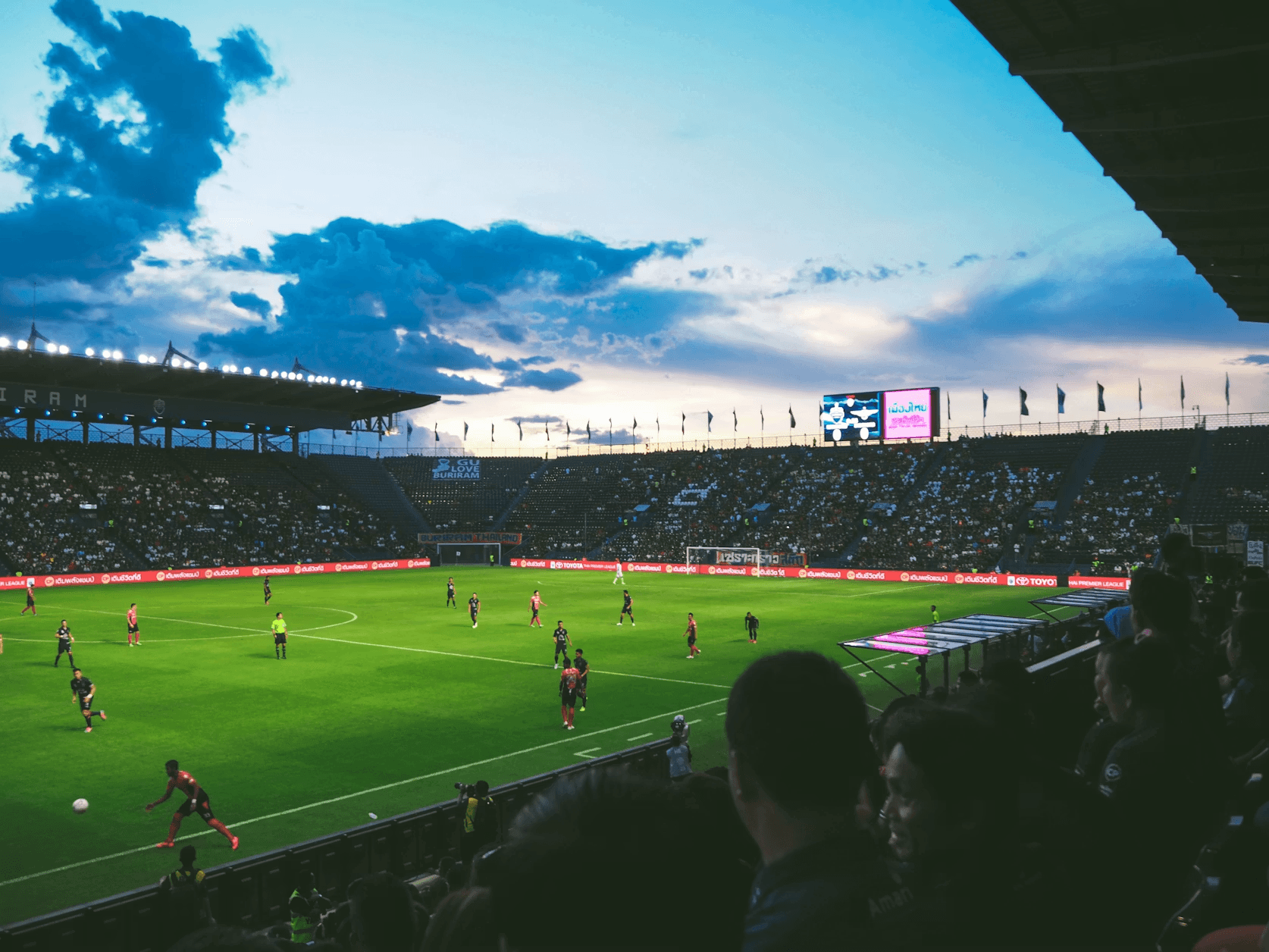 Football match in a packed stadium at dusk
